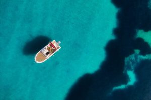 Vue aérienne d’un bateau au mouillage dans des eaux turquoise, symbole de détente et de navigation en Méditerranée à Port Camargue.