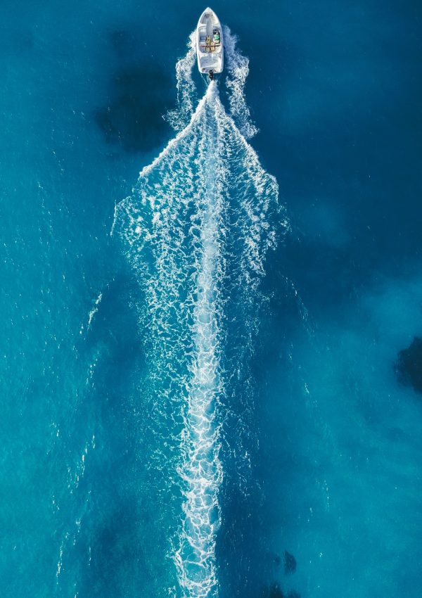 Bateau en action vu du ciel – Mer turquoise à Port Camargue Vue aérienne d’un bateau avançant à vive allure en laissant un long sillage sur une mer turquoise près de Port Camargue.