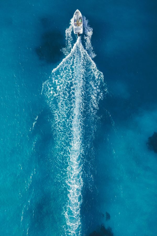 Bateau en action vu du ciel – Mer turquoise à Port Camargue Vue aérienne d’un bateau avançant à vive allure en laissant un long sillage sur une mer turquoise près de Port Camargue.