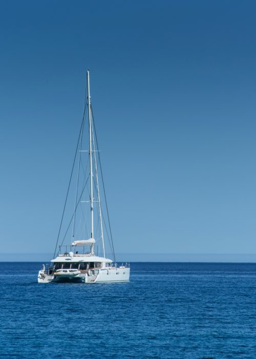 Catamaran en mer au large de Port Camargue – Permis bateau côtier Un catamaran blanc au large sur une mer calme et bleue, illustrant la navigation en mer ouverte pour le permis côtier.