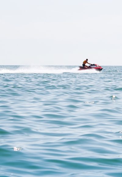 Jet-ski en mer à Port Camargue – Sensations et liberté Un homme en jet-ski glissant sur la mer calme sous un ciel clair à Port Camargue.