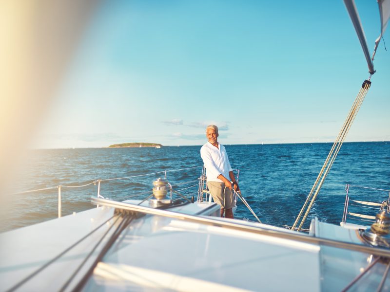 Mature man steering his sailboat on the open ocean Mature man steering his sailboat on the open ocean