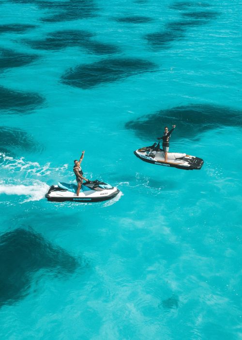 People riding jet skis on clear blue water, enjoying a sunny day People riding jet skis on clear blue water, enjoying a sunny day