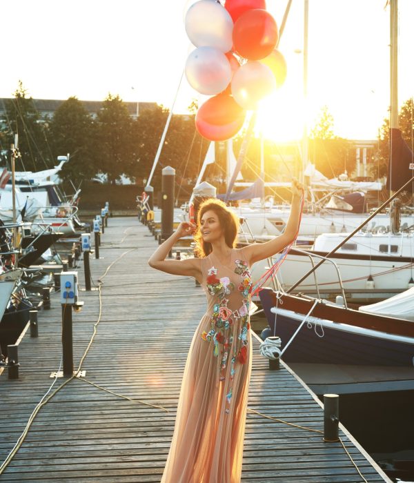 Woman in beautiful dress with a lot of colorful balloons on the yacht pier Woman in beautiful dress with a lot of colorful balloons on the yacht pier